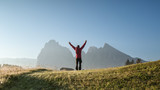 Fototapeta Na sufit - A man in the mountains with raised hands in a gesture of joy. Tourist in the mountains