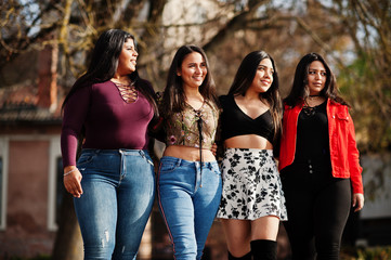 Wall Mural - Group of four happy and pretty latino girls from Ecuador posed at street.