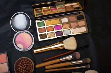 Set of make up brushes  with cosmetics on black background