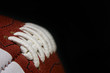 © KilmerMedia - An American football game ball is shown up close, with the focus showing the detail of the laces, stitching, and surface. A black area for copyspace / text space is to the right.
