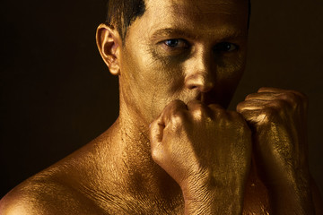 Body art paint with gold on face of man over dark background 