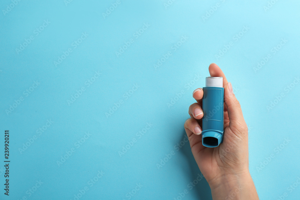 Woman holding asthma inhaler on color background, top view. Space for text - obrazy, fototapety, plakaty 