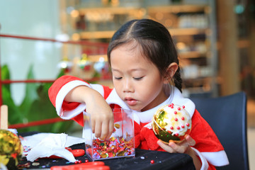 Cute little child girl making Christmas ball decoration ornament . Handmade New Year decorations.