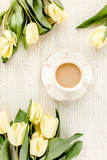 Fototapeta Tulipany - Yellow tulip flowers and cup of coffee. Flat lay, top view.