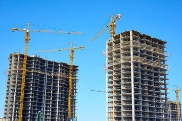 Building cranes and building under construction against sky.