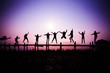 Silhouette Jumping team friends jumping on the wooden bridge on hill - happy and funny enjoy jumping people with sunrise