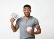 © Prostock-studio - Black man holding money and piggybank on white background
