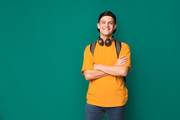 happy teenager with crossed arms over turquoise background
