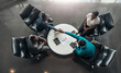 © JonoErasmus - Group of African business people sitting and discussing statistics during a sit down meeting taking from above. Two colleagues are shaking hands