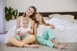 © dmitriisimakov - three girls sisters in the morning in the bedroom on the bed play
