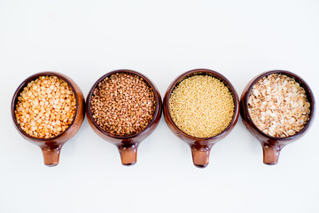 different types of groats in pots on a white background