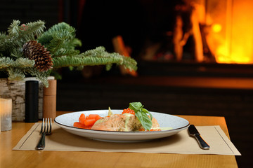 Wall Mural - salmon fillet with carrots, basil and red caviar, against the background of the Christmas tree and fireplace