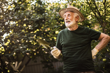 Aged man spending time at work in courtyard of country house