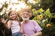© Yakobchuk Olena - Elderly man with his granddaughter standing between flowers