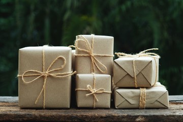 Stack of simple eco friendly gift box package wrap with brown paper in old wooden table background, green present concept