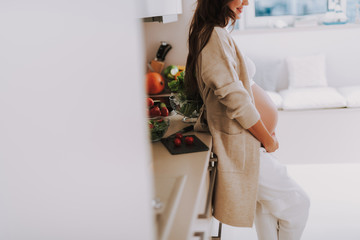 Wall Mural - Calm future mom standing on bright kitchen