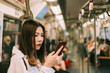 © grooveriderz - Business woman in subway using smartphone,Woman working on smart phone while traveling by train. Business travel concept.