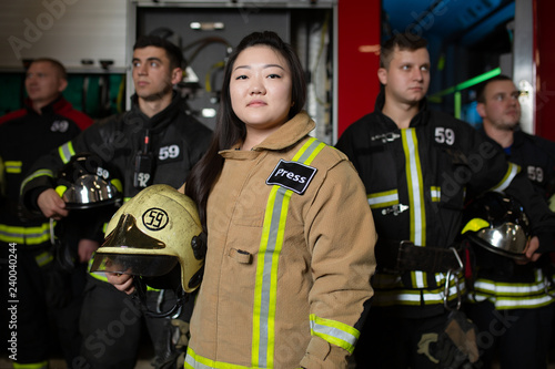 Photographie Portrait of four male and female firefighters on background of fire truck