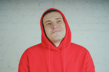 Wall Mural - Handsome guy posing by a brick wall. Crazy man in a red hoodie