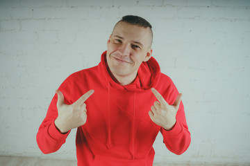 Wall Mural - Handsome guy posing by a brick wall. Crazy man in a red hoodie