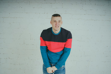 Wall Mural - Handsome guy posing against a brick wall. Crazy man in striped sweatshirt