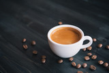 Fresh tasty espresso cup of hot coffee with coffee beans on dark background