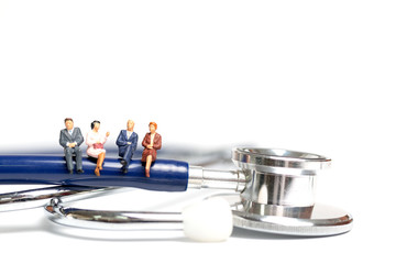 Miniature people sitting on a stethoscope on white background