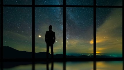 Wall Mural - The male standing near panoramic window on a starry sky background. time lapse