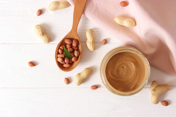 Wall Mural -  creamy peanut butter in a glass jar and peanuts beans on wooden background top view