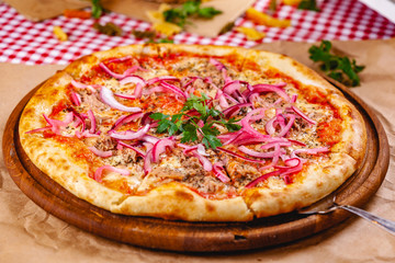 Wall Mural - Pizza with tuna and red onion on wooden cutting board. Close up