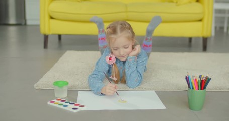 engrossed elemantary age girl with pigtails painting picture with paintbrush and colorful paints, ex