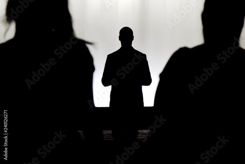 Fotografering Silhouettes of a mystery man standing , watching and confronting two blurry pers
