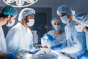 Canvas Print - Female nurses putting oxygen mask on patient in operation room. Jaw thrust maneuver technique for give oxygen and medication via mask from ventilator machine