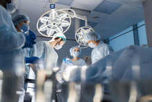Blurred Shot Of Group Of Professional Surgeons At Work In Operating Room. Emergency Case, Surgery, Medical Technology, Health Care Cancer And Disease Treatment Concept