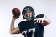© alfa27 - American football player wearing black helmet and jersey serving the ball in motion isolated over white background