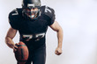 © alfa27 - American football player wearing black helmet and jersey serving the ball in motion isolated over white background