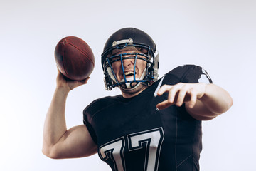 American football player wearing black helmet and jersey serving the ball in motion isolated over white background