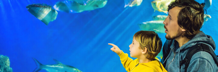 Wall Mural - Father and son look at the fish in the aquarium in oceanarium BANNER, LONG FORMAT