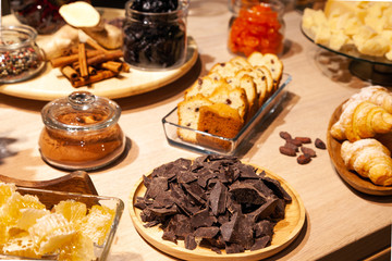 Closeup bakery and snacks, dried fruits, pieces parmesan cheese, honeycombs, dark chocolate, cinnamon sticks, raisin biscotti. Concept degustation premium catering at opening of store