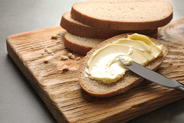 Spreading butter onto toast with knife on wooden board