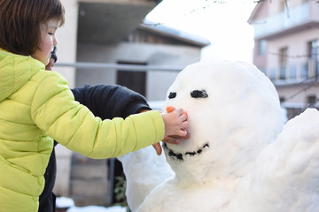 Wall Mural - Dad and son make a big snowman . Happy family play on snow in backyard