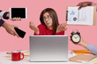 © WHstudio Leushin N - Clueless indecisive female model looks in bewilderment, shruggs shoulders, surrounded with papers, modern gadgets, alarm clock demonstrates she is short of time to prepare project, isolated on pink