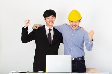 A young asian handsome business man and his co worker rised hands up and celebration the successful project. Co worker looking at laptop with happiness. Business working concept