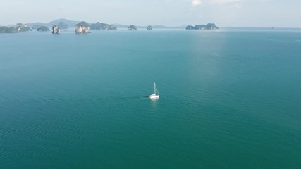 Wall Mural - Aerial view of a small sailing boat on a flat calm tropical ocean