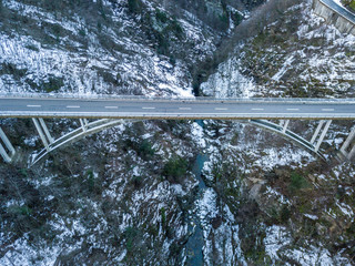 Wall Mural - Aerial view of road bridge in Switzerland over a deep valley in winter with snow covered ground. Icy conditions.