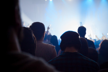 audience silhouettes crowd in large concert hall watching rock show.