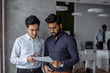 © alfa27 - Mix raced couple of male business partners planning next sales period. Indian and Korean male colleagues in formal shirts and studying documents in the big office room. Business concept