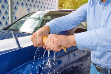 Wall Mural - A man’s hands are twisting a wet cloth at the car background.