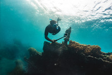 Freediver shooting on gopro coral reef with fish near wreckship