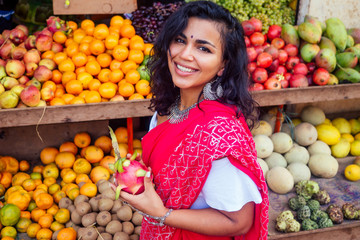 travel girl seller in street market and a buyer in a fruit shop in india delhi banknote money and customer buyer.smiling business woman indian in a red sari in kerala goa sell fruit and vegetable farm